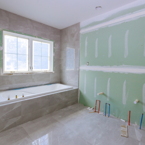 Plumber installing pipes in a bathroom remodel project with new tiles