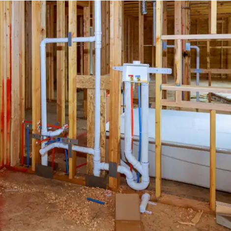 Plumber working on new construction bathroom piping within open framework